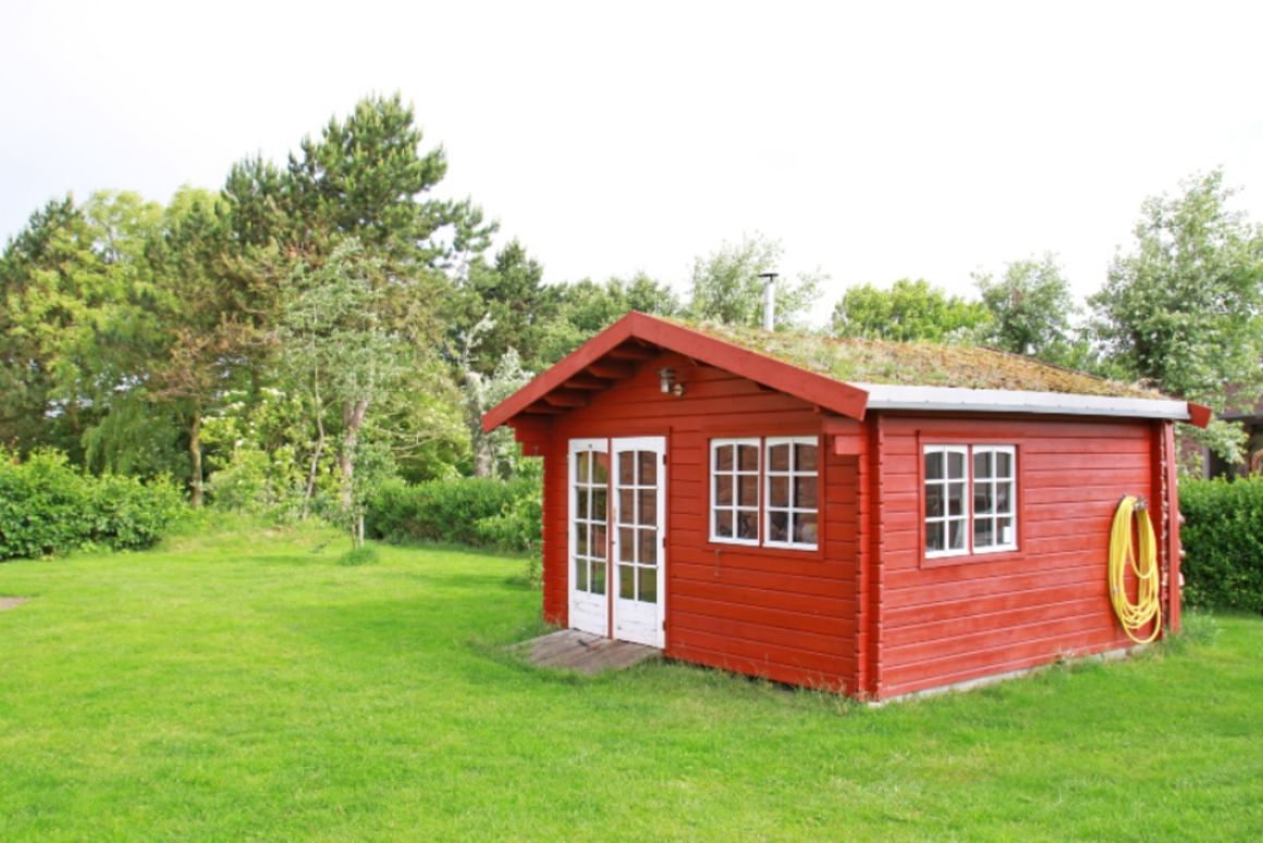 ein rotes Gartenhaus was auf einer Wiese steht
